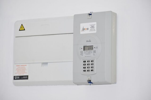 Contor de energie electrică montat pe peretele unei case, cu indexul vizibil pe afișaj